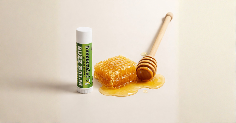 Natural beeswax lip balm tube next to honeycomb and honey dipper.