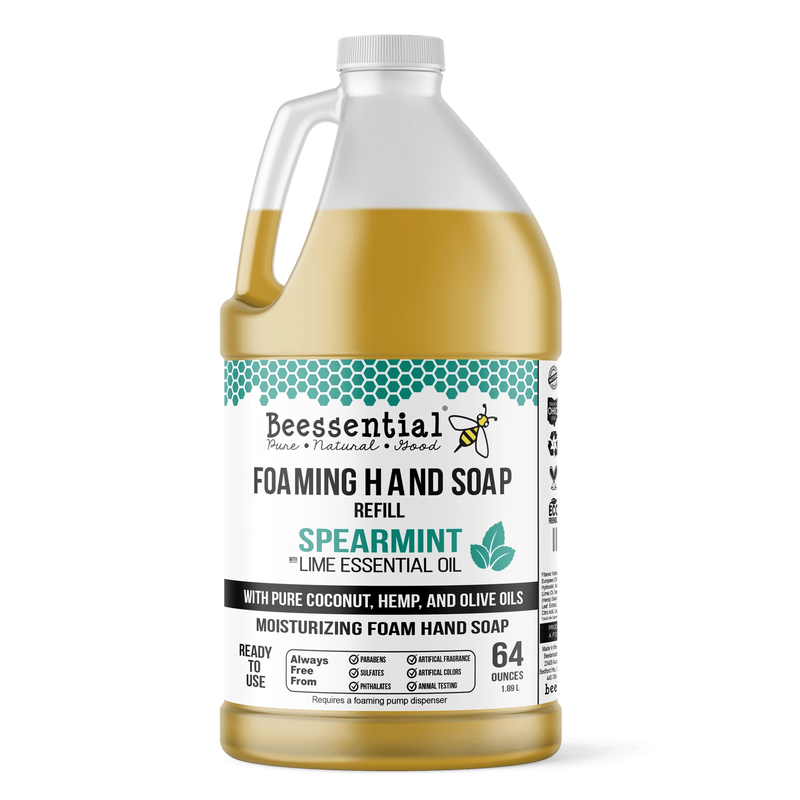A 64 oz plastic refill jug of Beessential Foaming Hand Soap in Spearmint scent, filled with golden-yellow oil and featuring a white label with teal accents, on a white background.